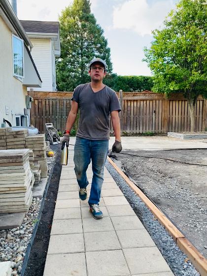 Walking the new path mid-lay, pavers stacked alongside