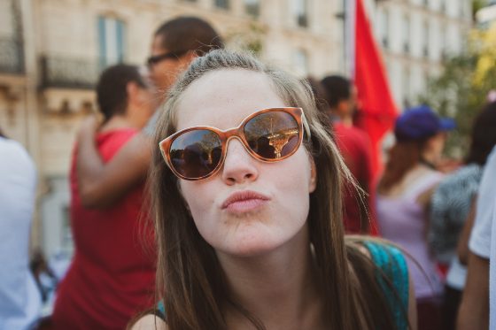A girl in the crowd, sunglasses, flag behind